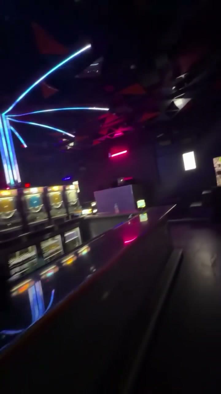 Neon light tubes fanning across the ceiling above the bar at night